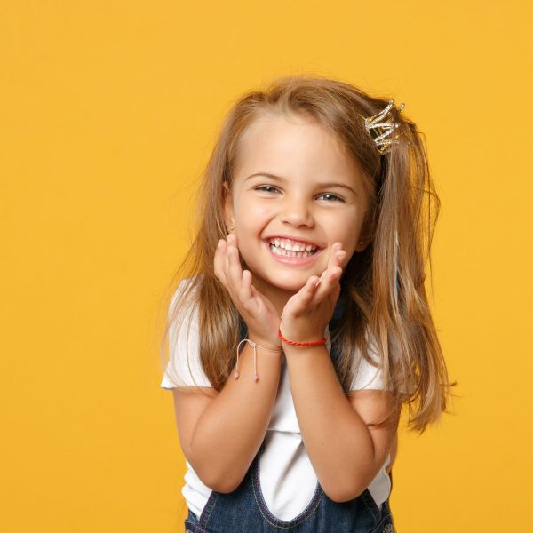 Little cute child kid baby girl 4-5 years old wearing light denim clothes isolated on pastel yellow wall background, children studio portrait. Mother's Day, love family, parenthood childhood concept